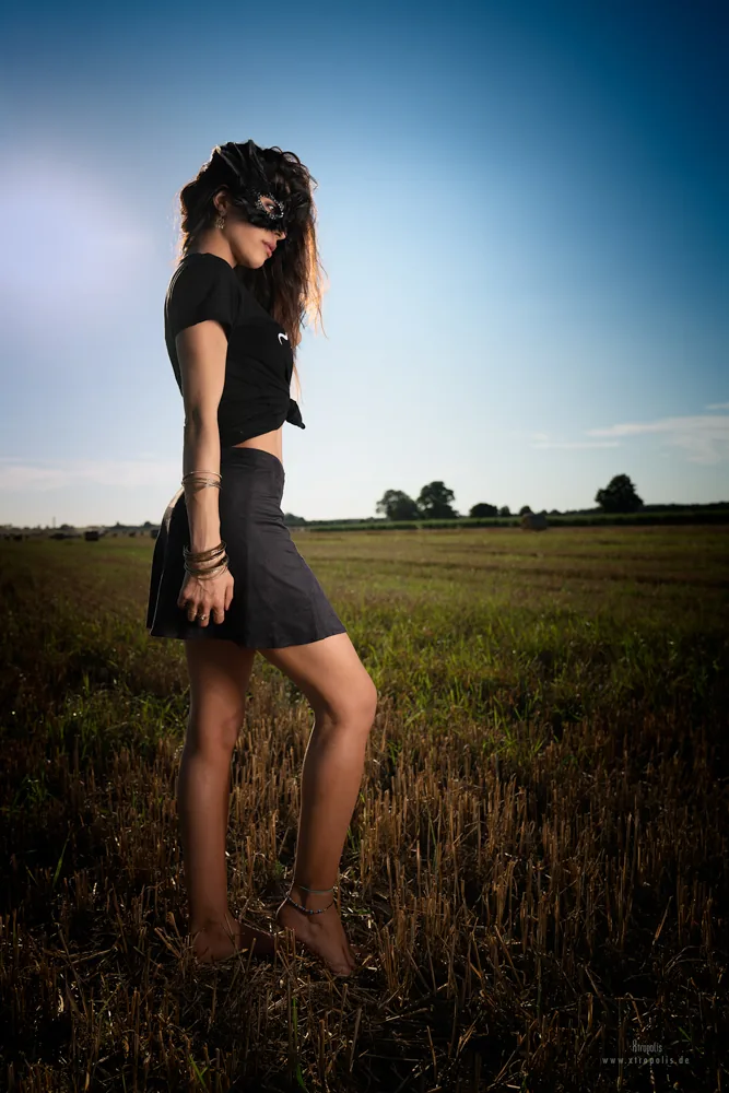 A woman in black in a stubble field at dusk
