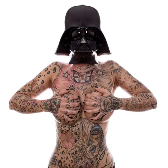 A tattooed person wearing a dark helmet