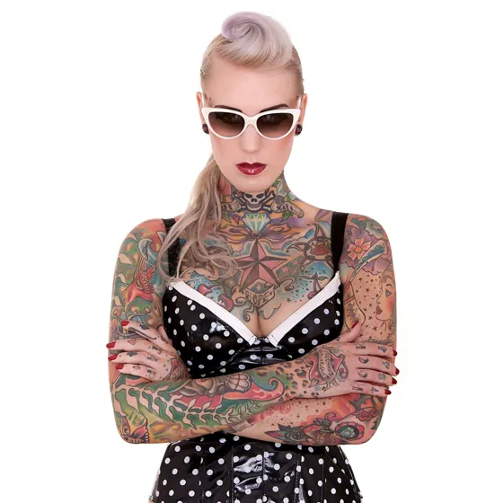 A tattooed woman with sunglasses in a polka-dot dress
